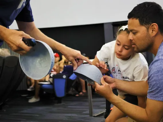 Father and daughter learn about the Moon with a 3d model of the lunar surface at a lecture at Flandrau planetarium in tucson